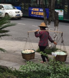Kunming Lady on her way to market with 2 large baskets of vegetables